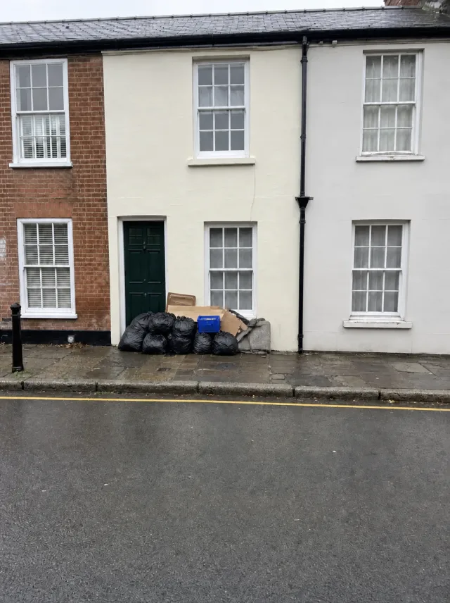Household clearance waste stacked on the pavement outside a cream-rendered period terrace in Old Amersham