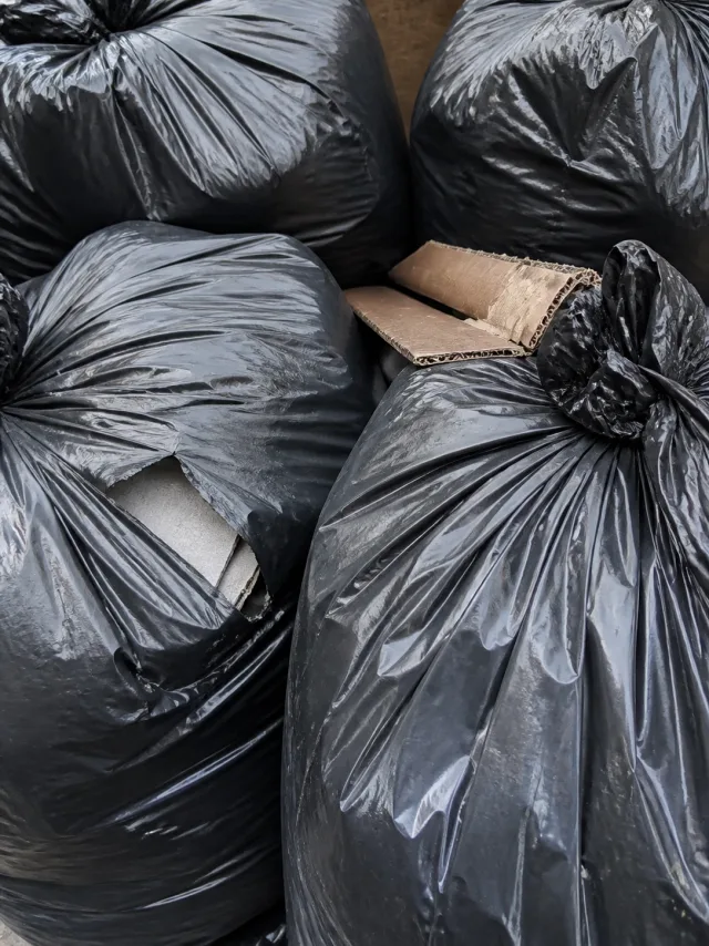 Close-up of tied black refuse sacks pressed together with cardboard wedged between them